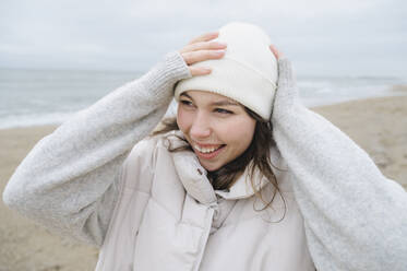 Glückliche Frau mit Strickmütze am Strand - ALKF00182