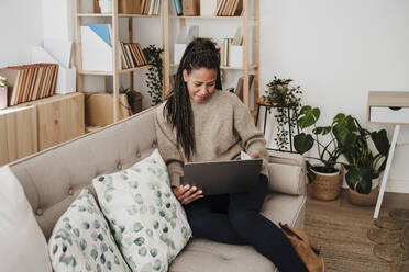 Reife Frau mit Laptop auf dem Sofa zu Hause sitzend - EBBF08213