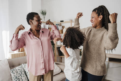 Happy family flexing muscles in living room at home - EBBF08223