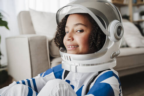 Smiling girl wearing space helmet at home - EBBF08247