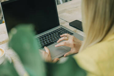 Geschäftsfrau tippt auf einem Laptop in einem Café - VSNF00589