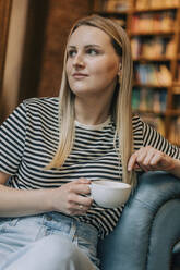 Nachdenkliche Frau mit Kaffeetasse im Café sitzend - VSNF00619