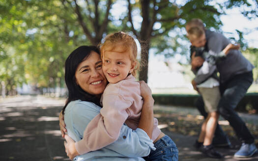 Ein glückliches kleines Mädchen, das seine Großmutter im Park umarmt. - HPIF08333