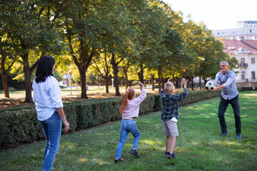 Glückliche kleine Kinder mit Großeltern spielen mit Ball im Freien in einem Park - HPIF08336