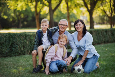 Happy little children with grandparents looking at camera outdoors in a park - HPIF08339