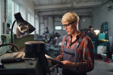 Ein Porträt einer jungen Frau, die in einer Metallwerkstatt arbeitet. - HPIF08346