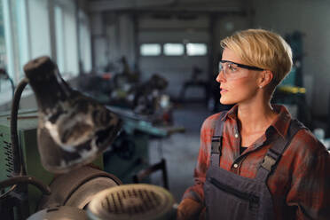 Ein Porträt einer jungen Frau, die in einer Metallwerkstatt arbeitet. - HPIF08347