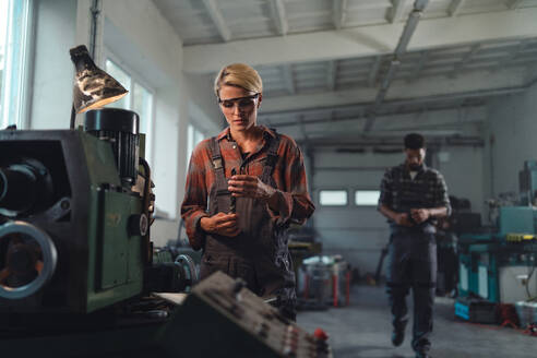 Ein Porträt einer jungen Frau, die in einer Metallwerkstatt arbeitet. - HPIF08355