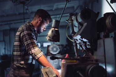 Porträt eines jungen konzentrierten afroamerikanischen Industriearbeiters, der in einer Metallwerkstatt an einer Fräse arbeitet. - HPIF08375