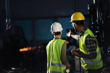 Eine Rückansicht von Industrieinspektoren, die eine allgemeine Kontrolle in einer Metallwerkstatt durchführen. - HPIF08382