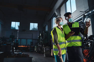 Ein Industrieinspektor mit Gesichtsmaske bei einer allgemeinen Kontrolle in einer Metallwerkstatt, Coronavirus-Konzept. - HPIF08391