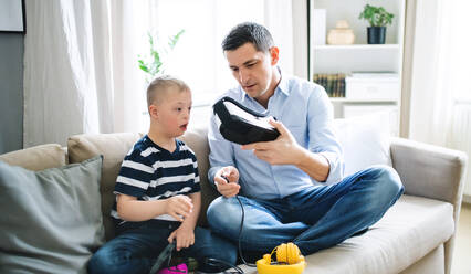 Ein Vater mit einem glücklichen Sohn mit Down-Syndrom zu Hause, der eine VR-Brille benutzt. - HPIF08403