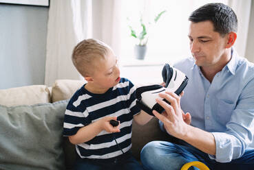 Ein Vater mit einem glücklichen Sohn mit Down-Syndrom zu Hause, der eine VR-Brille benutzt. - HPIF08404