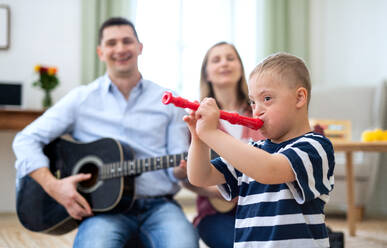 A cheerful down syndrome boy with parents playing musical instruments, laughing. - HPIF08435