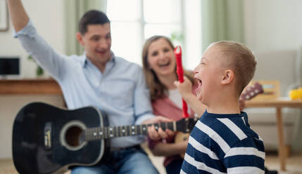 A cheerful down syndrome boy with parents playing musical instruments, laughing. - HPIF08436