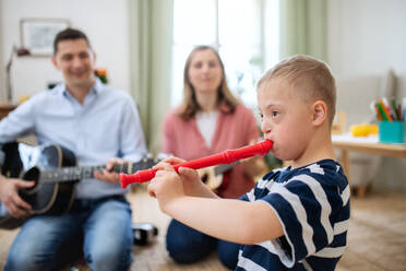 A cheerful down syndrome boy with parents playing musical instruments, laughing. - HPIF08437