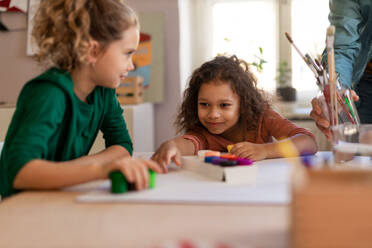 Happy little girls preparing for an art class indoors at school - HPIF08460