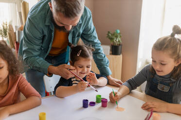 Eine Gruppe kleiner Kinder arbeitet mit ihrem Lehrer an einem Projekt während des kreativen Kunst- und Handwerksunterrichts in der Schule. - HPIF08462