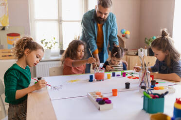 Eine Gruppe kleiner Kinder arbeitet mit ihrem Lehrer an einem Projekt während des kreativen Kunst- und Handwerksunterrichts in der Schule. - HPIF08463