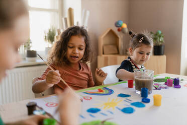 Happy little girls painting a picture during creative art and craft class at school. - HPIF08464