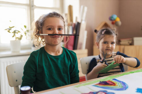 A happy little girl with her friends preparing for art class indoors at school - HPIF08467