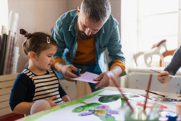 Eine Gruppe kleiner Kinder arbeitet mit ihrem Lehrer an einem Projekt während des kreativen Kunst- und Handwerksunterrichts in der Schule. - HPIF08469