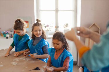 A group of little kids working with pottery clay during creative art and craft class at school. - HPIF08493