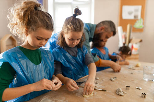 Eine Gruppe kleiner Kinder mit einem Lehrer, die während des Kunst- und Bastelunterrichts in der Schule mit Ton arbeiten. - HPIF08496