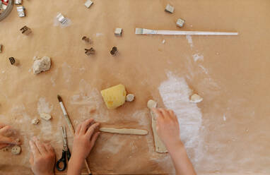 The hands of children molding mud on table top view during art class. - HPIF08499