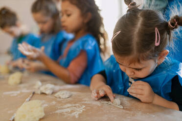 Eine Gruppe kleiner Kinder, die im Rahmen des kreativen Kunst- und Handwerksunterrichts in der Schule mit Töpferton arbeiten. - HPIF08500