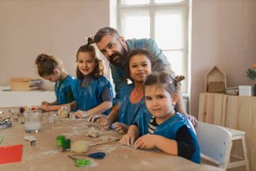 A group of little kids with teacher working with pottery clay during creative art and craft class at school. - HPIF08502