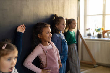 Eine Gruppe kleiner Mädchen posiert vor einer Wandtafel in einem Spielzimmer. - HPIF08504