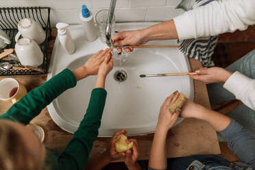 Nahaufnahme von kleinen Mädchen, die sich nach dem Kunstunterricht im Schulbad die Hände und Pinsel im Waschbecken waschen. - HPIF08527