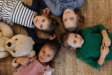 A top view of of little girls friends lying on back on floor and looking at camera. - HPIF08528