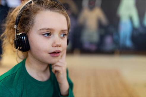 Ein kleines Mädchen mit Kopfhörern und Mikrofon hört Musik, hat Spaß und spielt zu Hause. - HPIF08529
