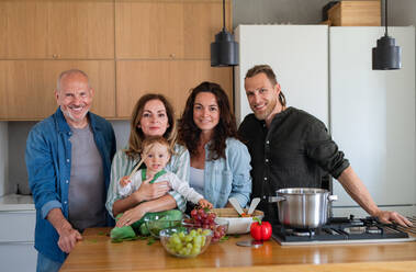 Porträt einer glücklichen Mehrgenerationenfamilie, die zu Hause kocht und in die Kamera schaut. - HPIF08543