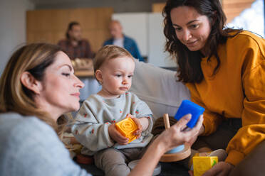 Eine glückliche Mehrgenerationen-Familie, die mit einem kleinen Baby zu Hause spielt, Besuchskonzept. - HPIF08558