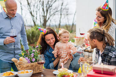 A happy multigeneration family outdoors in garden at home, birthday celebration party. - HPIF08570