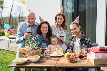 A happy multigeneration family outdoors in garden at home, birthday celebration party. - HPIF08573