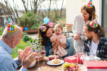 A happy multigeneration family outdoors in garden at home, birthday celebration party. - HPIF08575