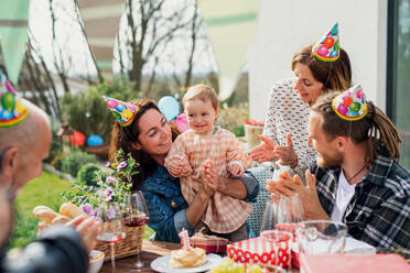 A happy multigeneration family outdoors in garden at home, birthday celebration party. - HPIF08576