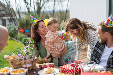 A happy multigeneration family outdoors in garden at home, birthday celebration party. - HPIF08577