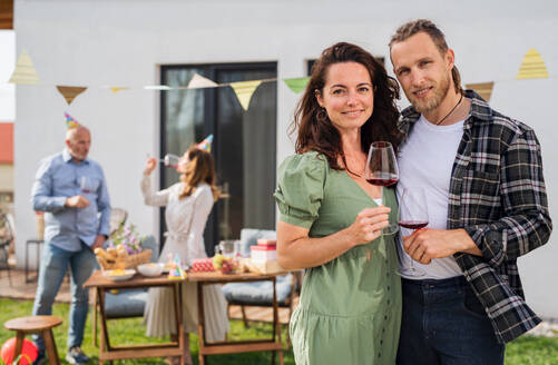 Ein junges Paar mit Wein im Freien im Garten zu Hause, Geburtstagsfeier Party. - HPIF08579