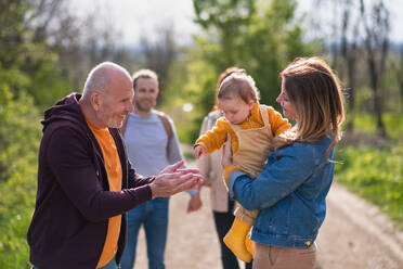 A multigeneration family with toddler on a walk outdoors in nature, having good time. - HPIF08589