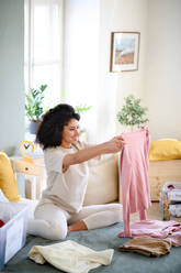 Glückliche junge Frau, die ihre Garderobe zu Hause sortiert, Konzept der Wohltätigkeitsspende. - HPIF08671