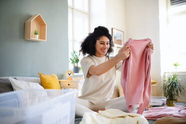 Glückliche junge Frau, die ihre Garderobe zu Hause sortiert, Konzept der Wohltätigkeitsspende. - HPIF08673