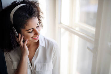 Ein Porträt einer jungen Frau mit Kopfhörern zu Hause, die Musik hört. - HPIF08697