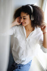 A portrait of young woman with headphones indoors at home, listening to music. - HPIF08699