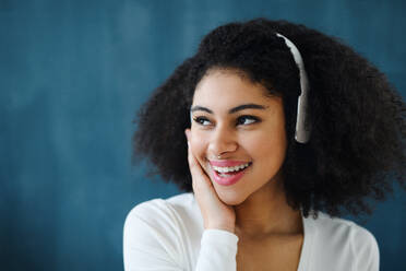 A portrait of young woman with headphones indoors at home, listening to music. - HPIF08719