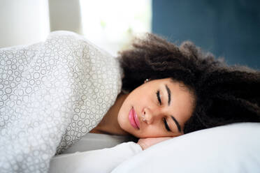 Porträt einer jungen Frau mit geschlossenen Augen in einem Zimmer, die im Bett schläft. - HPIF08721